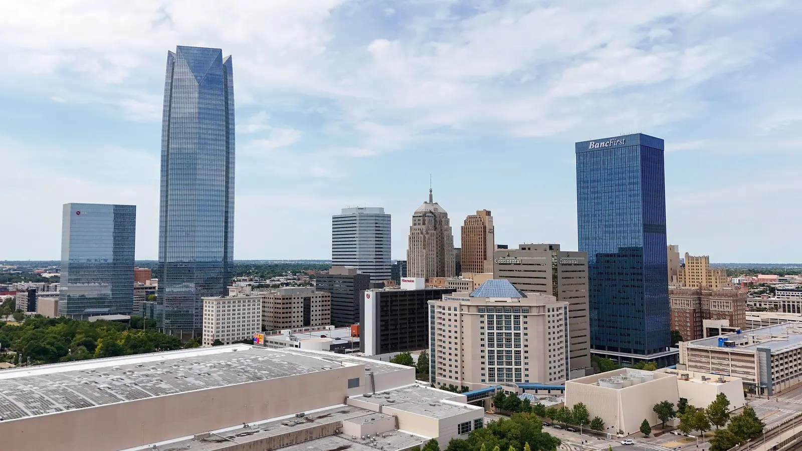 Aerial view of downtown Oklahoma City on a summer day, with Devon Energy Center and BancFirst Tower rising above lower downtown buildings