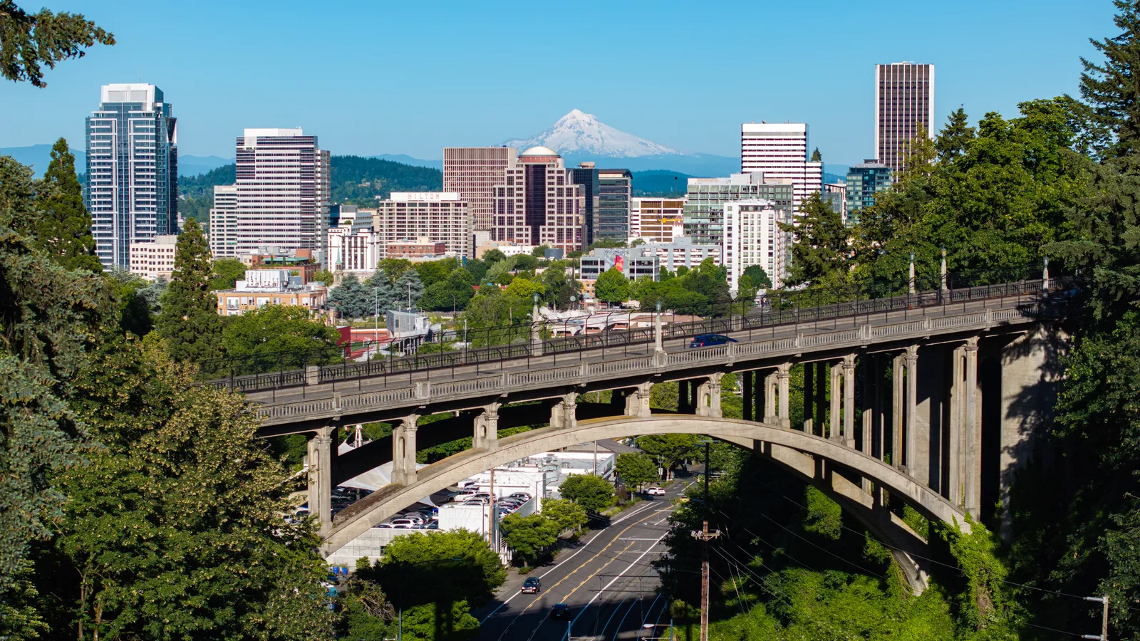 Downtown Portland, Oregon, with Mount Hood behind it and the arched Vista Bridge over a street in the foreground